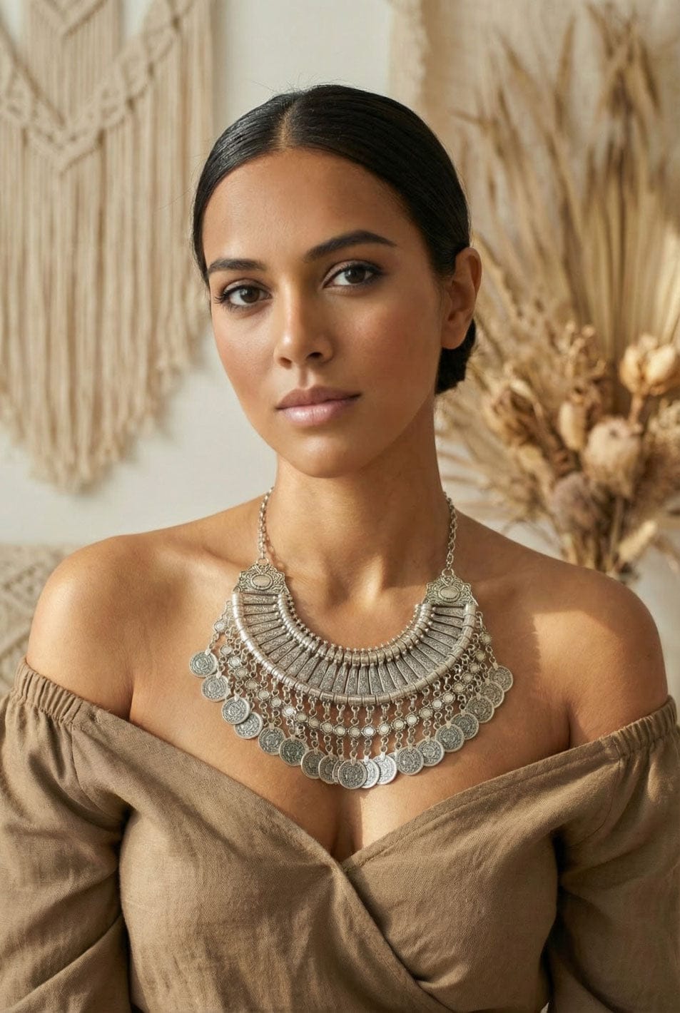 Woman wearing a large silver necklace against a neutral background
